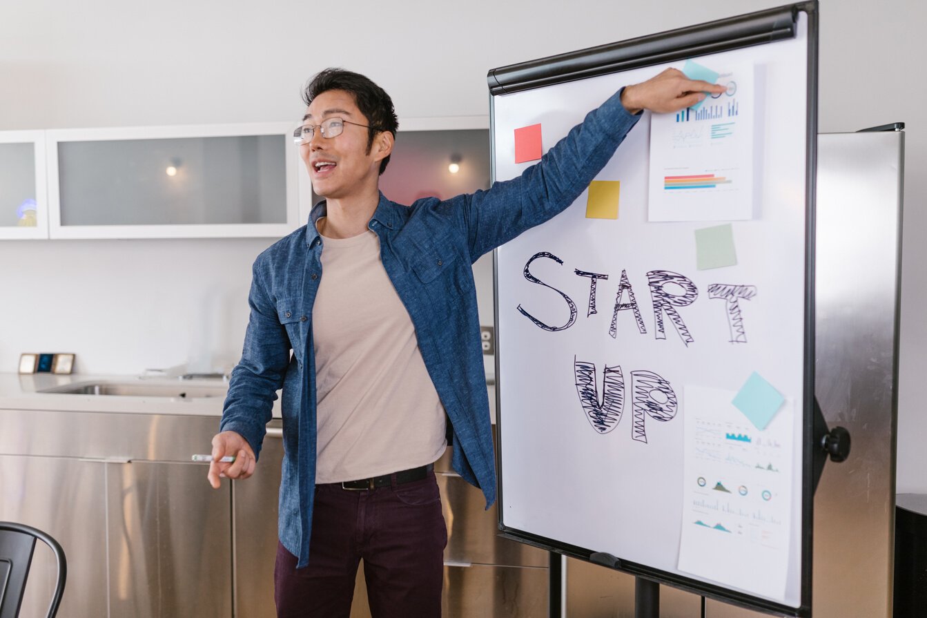 Man in Blue Denim Jacket Standing Near the White Board